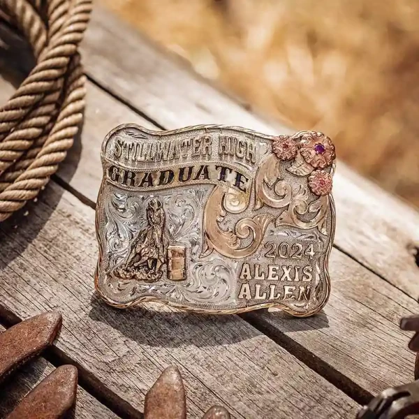 A custom graduation belt buckle for Stillwater High School graduate featuring a barrel racing cowgirl figure 